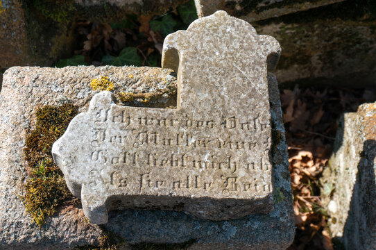 Part of old stone cross with inscription, kirkyard. Winniki (village&nbsp;in West Pomeranian Voivodeship, Gmina Węgorzyno), Poland.