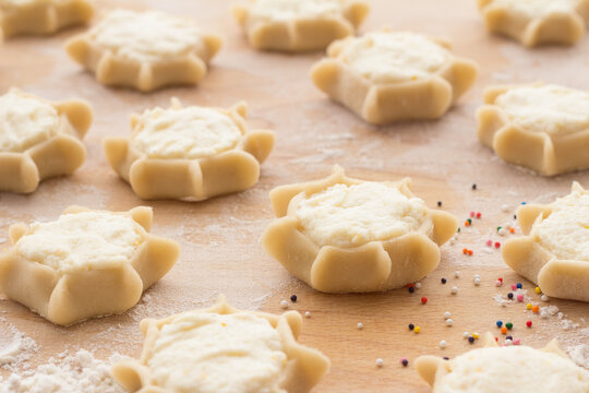Process of making traditional Italian ricotta cheese pastries on wooden board with flour and colorful sprinkles