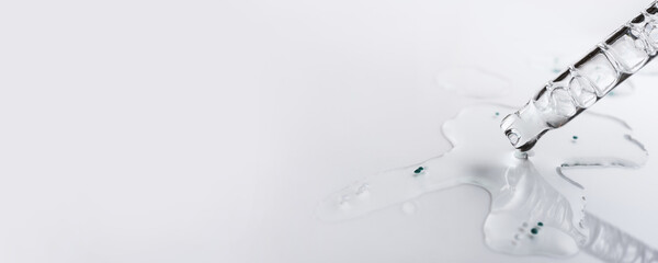 Fototapeta premium Clear liquid serum with active ingredients spilling from pipette, banner format