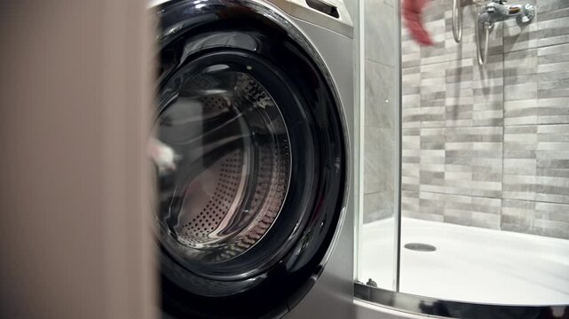 closing the Washing machine door opens revealing interior drum in modern bathroom setting