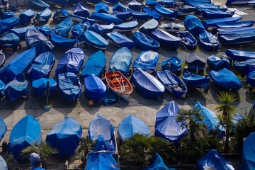 Obraz premium Aerial View of Boats Covered with Blue Tarps in Marina Storage Yard with One Red Rowboat Standing Out. Wnter Boat Storage.