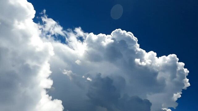 Low Angle Shot of Puffy White Clouds Against Deep Blue Sky with Sun Glare Above