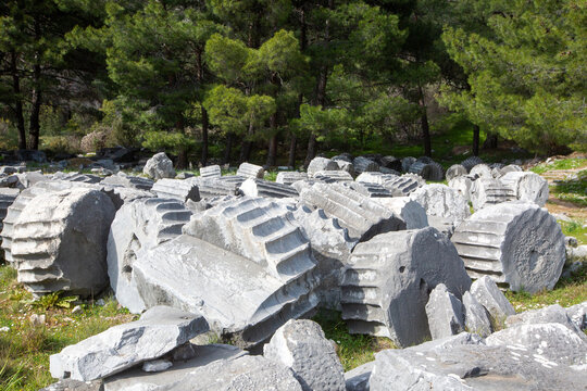 Ruined columns of Athena Temple with acropolis cliff in ancient city Priene Turkey