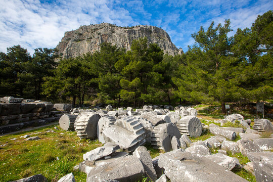 Ruined columns of Athena Temple with acropolis cliff in ancient city Priene Turkey