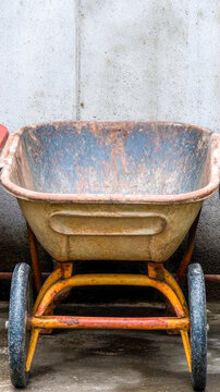 Three wheelbarrows stacked alongside a wall, awaiting use or storage