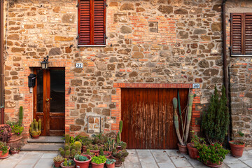 Fototapeta premium Traditional stone architecture and potted plants in Montalcino street, Italy.