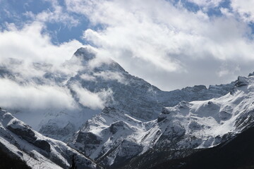 Obraz premium Autumn scenery of Xuebao Peak (Xuebao Snow Mountain) in the Minshan Mountain with dramatic clouds and forest in a sunny day, Songpan County, Sichuan Province of China