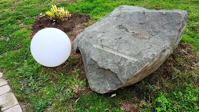 A round glass lamp near a large stone