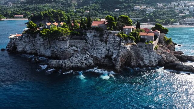 Aerial view of Sveti Stefan, a rocky islet crowned with terracotta-roofed buildings, contrasting against the deep blue Adriatic, Sveti Stefan, Budva Municipality, Montenegro.