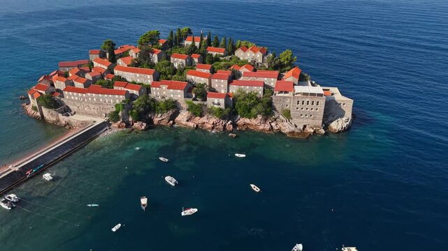 Aerial view of Sveti Stefan island with its red-roofed buildings contrasting against the deep blue sea, Sveti Stefan, Budva Municipality, Montenegro.