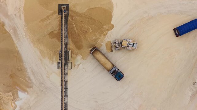 Aerial view of trucks and machinery at work in a quarry, contrasting against the textures of the extracted material, Arsoli, Lazio, Italy.