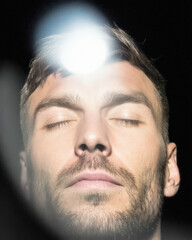 Man with closed eyes and radiant light from above