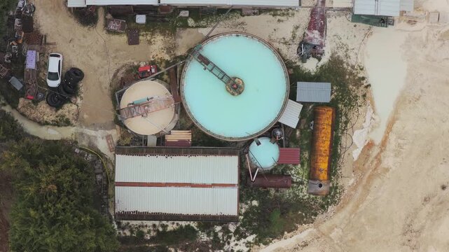 Aerial view of an industrial complex featuring circular tanks and rusty structures, contrasting textures against the muted earth tones, Arsoli, Lazio, Italy.