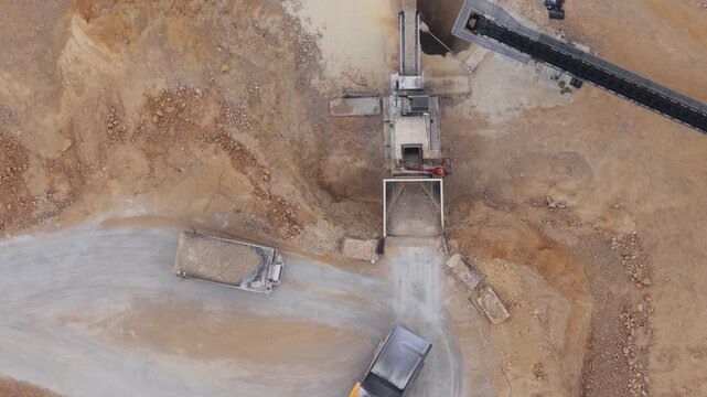 Aerial view of a quarry, where trucks and machinery work in a landscape of contrasting earth tones, creating a scene of industrial activity, Arsoli, Lazio, Italy.