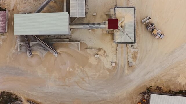 Aerial view of a sprawling industrial site with buildings, machinery, and stockpiles of raw materials, presenting a stark contrast against the earth tones, Arsoli, Lazio, Italy.