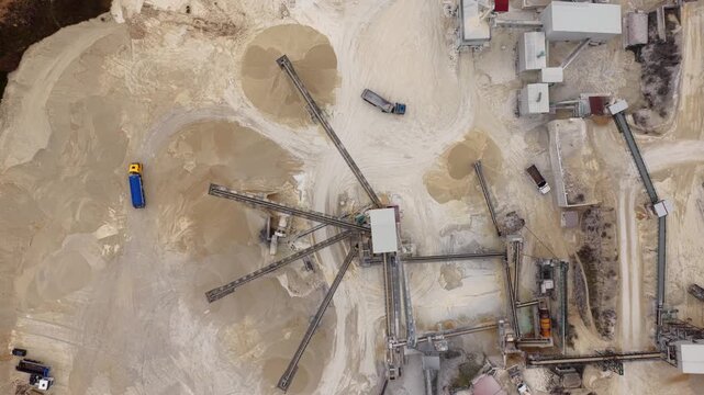 Aerial view of an industrial quarry showing piles of sand, conveyor belts, and trucks, a landscape of extraction and industry, Arsoli, Lazio, Italy.