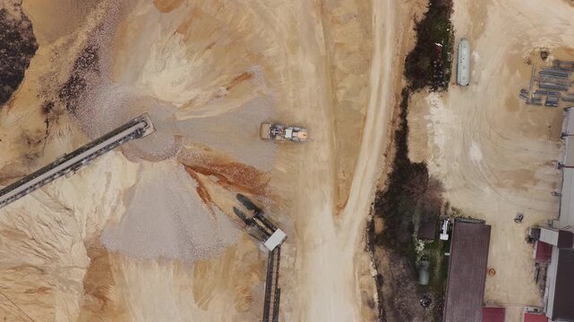 Aerial view of a vast industrial site featuring piles of earth, machinery, and buildings, displaying a stark contrast of textures and tones, Arsoli, Lazio, Italy.