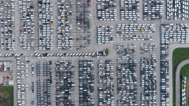 Aerial view of tightly packed rows of vehicles, a stark contrast of light and shadow, creating geometric patterns across the landscape, Atessa, Abruzzo, Italy.
