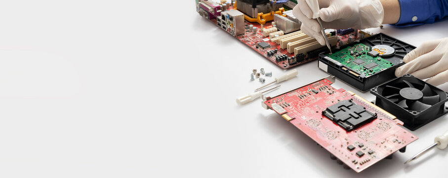 Banner of Computer Technician work, empty space. Motherboard, hard disk drive, other parts of computer on white desk and IT support specialist hands who fixing computer