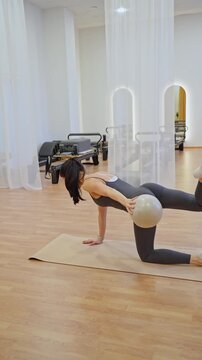 Athletic woman holding arm and leg out, balancing in quadruped pilates pose in bright studio. Quadruped pose, pilates, arm leg out, bright, athletic.