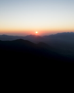 Aerial view of Mount Terminio at sunset with silhouetted mountain peaks under a glowing orange sky Sala, Campania, Italy.