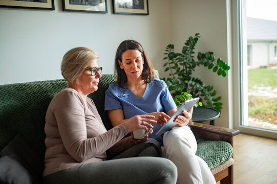 Physiotherapist explaining treatment plan to senior woman during home care visit.