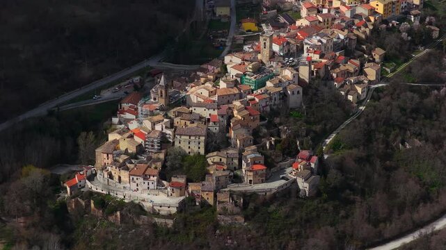 Aerial view of Cocullo, a hilltop town showcasing buildings with red roofs nestled amid lush greenery, Cocullo, Abruzzo, Italy.