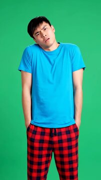 Surprised Asian Man Reaction wearing blue t-shirt and plaid pants on green screen ideal for video editing and social media content. Vertical. Video. Portrait Orientation.