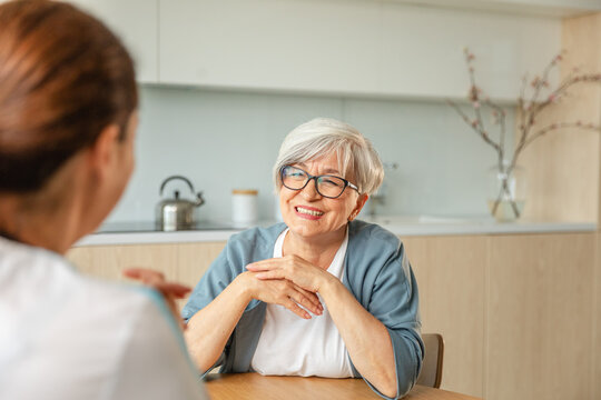 Female doctor examining older senior woman in doctor office or at home. Old woman lady patient and doctor have consultation in hospital room. Medicine healthcare medical checkup. Visit to doctor