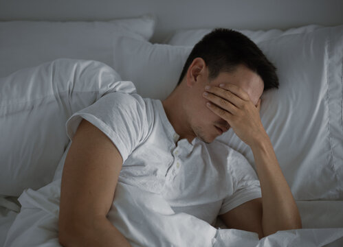 Tired man in bed, stress burnout and mental health concept