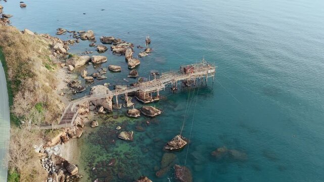 Aerial view of Trabucco, where the wooden structure contrasts against the blue sea, and the rocky coastline, San Vito Chietino, Abruzzo, Italy.
