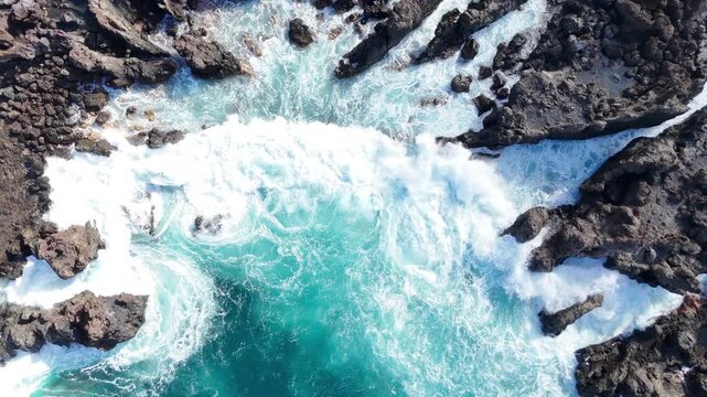 Aerial shot of ocean waves crashing against rocky coastline, showcasing the dynamic interplay of water and rocks in a vibrant coastal landscape. Sea water splashing over coastline. Close up Top View