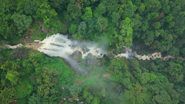 Aerial view of the majestic Curugsewu Waterfall cascading through the vibrant green forest, a stunning display of nature's power, Curugsewu, Central Java, Indonesia.