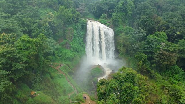 Aerial view of Curugsewu Waterfall cascading amidst lush green trees and a stairway leading up the hill, Curugsewu, Central Java, Indonesia.