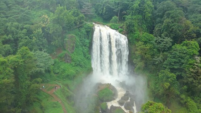 Aerial view of the majestic Curugsewu Waterfall cascading through lush green forests, creating a misty spectacle of nature's artistry, Curugsewu, Central Java, Indonesia.