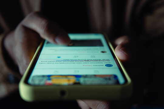 Person scrolling news feed on digital device at night
