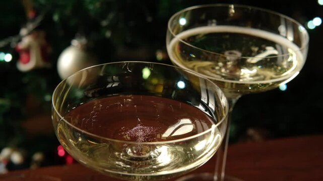 bubbles of prosecco champagne or sparkling white wine in elegant glasses against the background of a decorated Christmas tree and festive lights