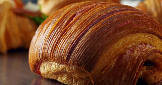 Cinematic dolly close-up shot revealing the flaky texture of a chocolate millefoglie croissant. Smooth camera movement enhances layers and golden surface in soft light.