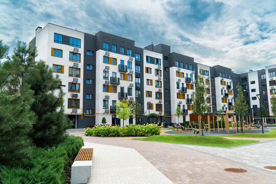 Modern residential apartment complex exterior with landscaped park area, outdoor gym and workout zone, contemporary urban housing development