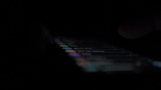 Man Scrolling Social Media on Smartphone at Night
