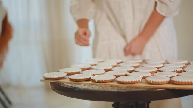 Rows of mini pumpkin pies on rotating stand caucasian woman in vintage dress arranges pies gently dusts edges warm window light homestyle kitchen intimate cozy mood holiday preparation