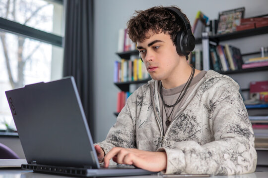 High school student preparing for exams using laptop and books. Teenager studying at desk with laptop, modern education concept