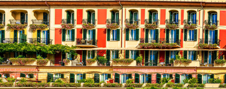 beautiful red and orange hotel facade of house with three green plants and braches and windows in retro italian european style