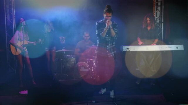 Lead singer leaning to mic, starting music band playing onstage, singing song, bokeh intensifying
