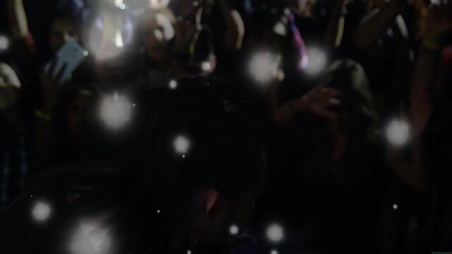 Singer moving through music club to engage fans, audience lighting phones, bokeh drifting over mic