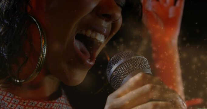 Female singer holding mic close singing loud then soft, engaging music crowd, particles around her