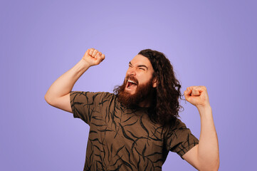 Ecstatic Man Raising Fists In Triumph, Openmouthed Cheer With Curly Hair And Beard Against Purple Backdrop © Vulp