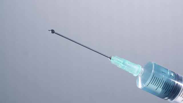 Blue drops come from a syringe, may be is a vaccine or anesthesia