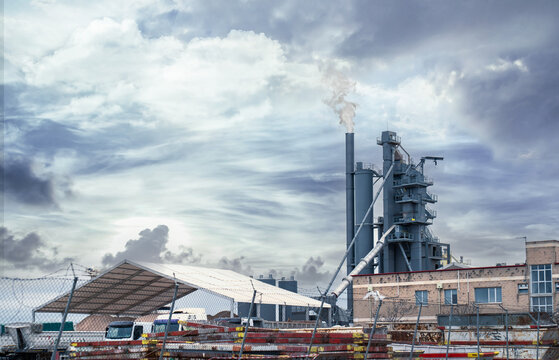 Industrial factory chimney emitting smoke, contributing to air pollution against a stormy sky