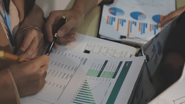 Close up of businessman or accountant hand holding pen working on calculator to calculate business data, accountancy document and laptop computer at office, business concept